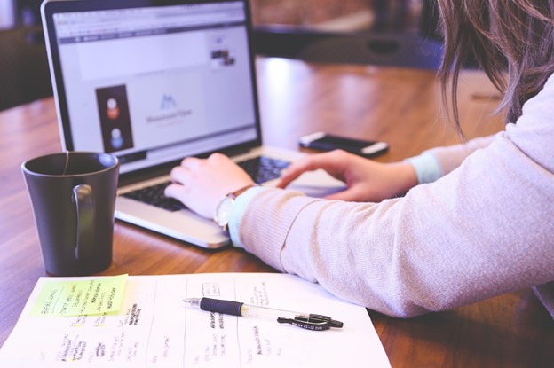 A woman working on a laptop with a notebook